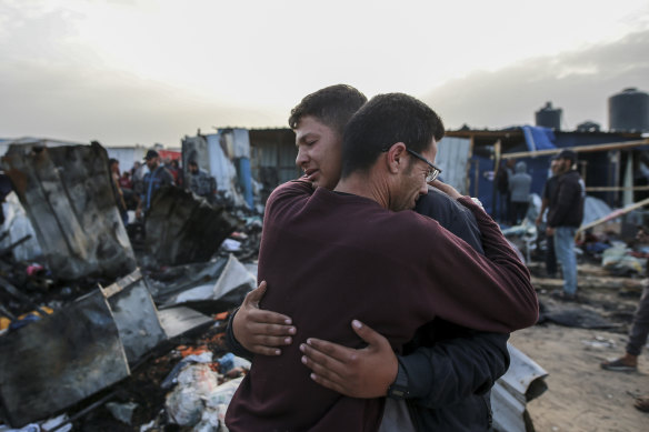 Palestinians react next to the destruction after an Israeli strike where displaced people were staying in Rafah.