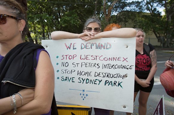 A woman holds a sign protesting against the Westconnex development at Sydney Park.