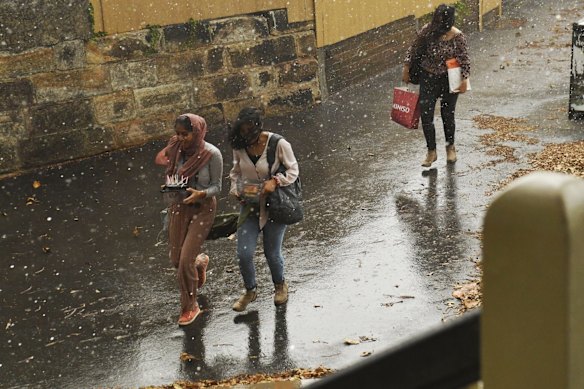 Picnickers run for cover as strong winds and rain hit Observatory Hill in Sydney.
