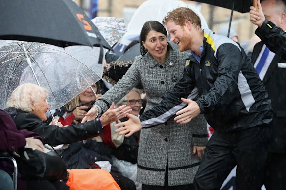 Prince Harry hugs 97 year old Daphne Dunne during a walkabout in the torrential rain at the Overseas Passenger Terminal on June 7, 2017 in Sydney, Australia.