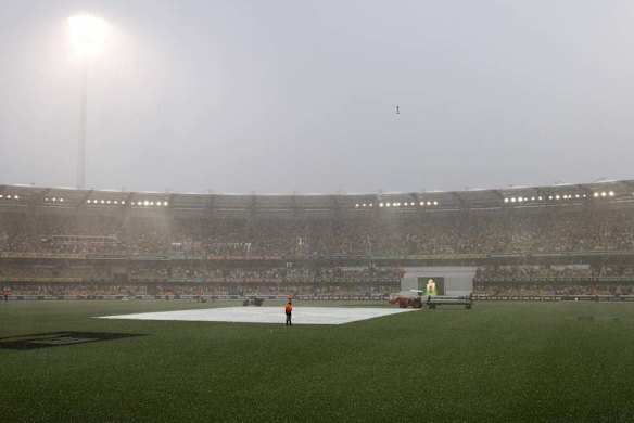 A security guard watches the pitch during a rain storm that interrupted play on the fourth day of the series-opening Ashes cricket test between England and Australia at the Gabba in Brisbane, Australia, Sunday, Nov. 24, 2013. (AP Photo/Tertius Pickard)