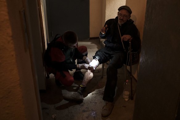A man is treated by an emergency worker in the hallway of an apartment building before being taken to hospital, following a Russian bombardment in Kharkiv.