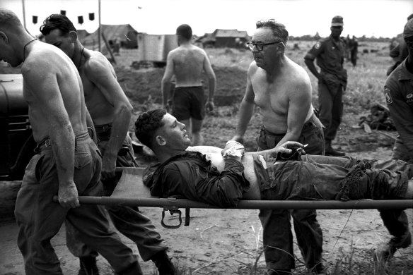 A 1st Battalion soldier, accompanied by Salvation Army Brigadier Aubrey Hall, is carried on a stretcher on June 26, 1965. 