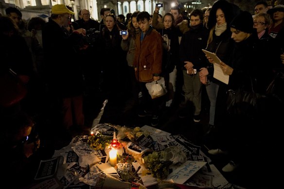 Flowers rest on top of a pile of pens and posters that read 'I am Charlie'.