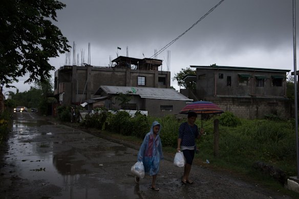 Evacuees carry relief goods distributed by local government workers at a temporary evacuation centre .