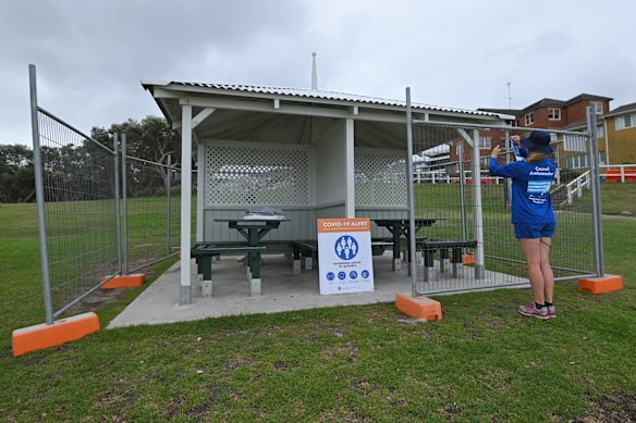 A Waverley Council worker puts up warning signs on huts that are fenced off as a precaution against Coronavirus on New Years Eve at Bronte Beach in Sydney.