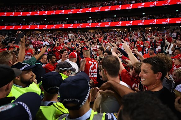 Lance Franklin of the Swans is surrounded by fans on the field.