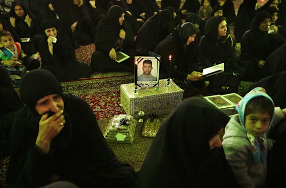 Women surround a framed photo of asylum seeker Reza Barati, during the memorial service.