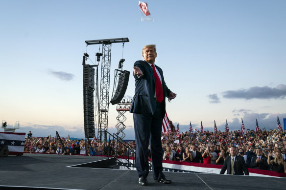 President Donald Trump throws face masks into the crowd as he arrives for a campaign rally at Orlando Sanford International Airport.