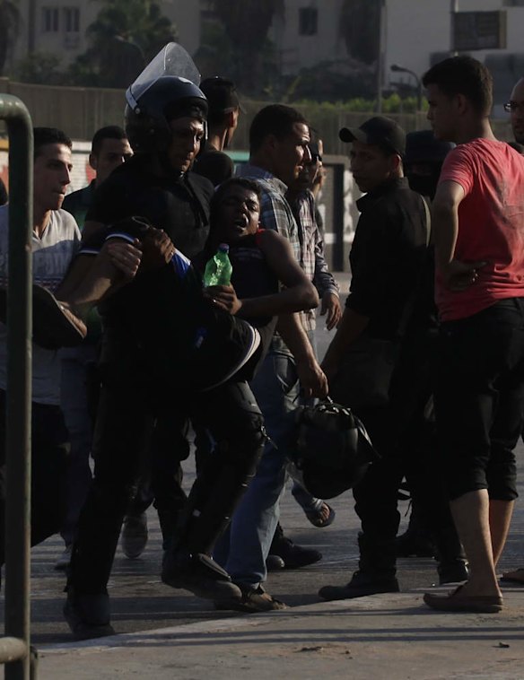 A riot police officer carries a youth during clashes between supporters of ousted Egyptian President Mohamed Mursi and security forces near Rabba el Adwia Square, where the protesters are camping, in Cairo.