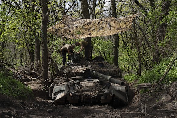 Ukrainian servicemen install a machine gun on a tank during repair works after fighting against Russian forces in the Donetsk region.