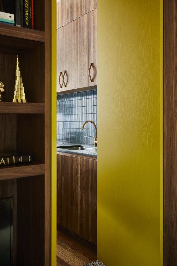 A door painted in Dulux’s Balsam Pear leads to the kitchen. The bespoke joinery in walnut veneer was designed by Liz, providing storage for media, books and objects.