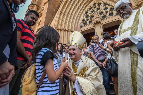 Archbishop of Sydney, Anthony Fisher hands out Easter eggs after  mass. 