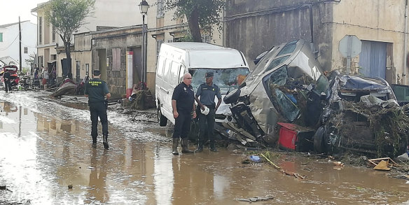 Police officers stand next to vehicles destroyed in the flash floods. 