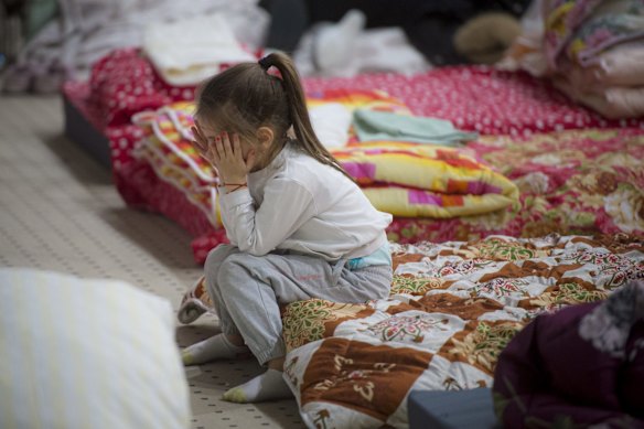 A refugee who fled the conflict in neighbouring Ukraine covers her face as she sits in a hotel that's being used as an emergency shelter in Siret, Romania.