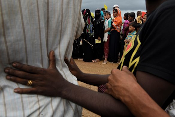 Rohingya women queue at a distribution site after a monsoonal downpour in Hakim Para Camp. 