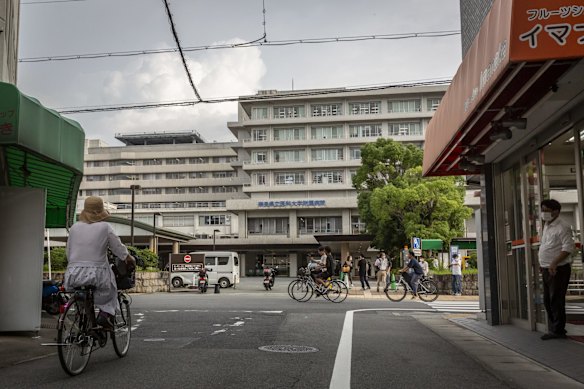 People cycle past Nara Medical University Hospital where Shinzo Abe was rushed via helicopter following the shooting.