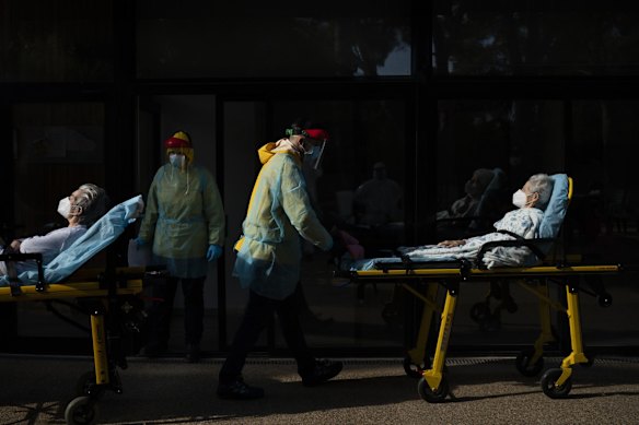 Health workers carry on a stretcher two elderly residents of a nursing home who tested positive for the new coronavirus in Barcelona, Spain.