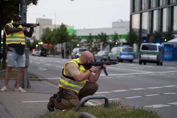 Police officers point their weapons outside the Olympia mall.