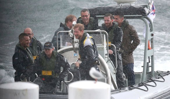 Britain's Prince Harry, center, braves the rain as he arrives by boat to meet well-wishers during a short walk in Sydney, June 7, 2017.