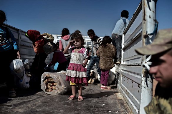 Refugees from the Syrian town of Ain al-Arab, known as Kobane by the Kurds, get on a truck after crossing the Turkish border with Syria near the city of Sanliurfa on October 4, 2014. Photo by AFP