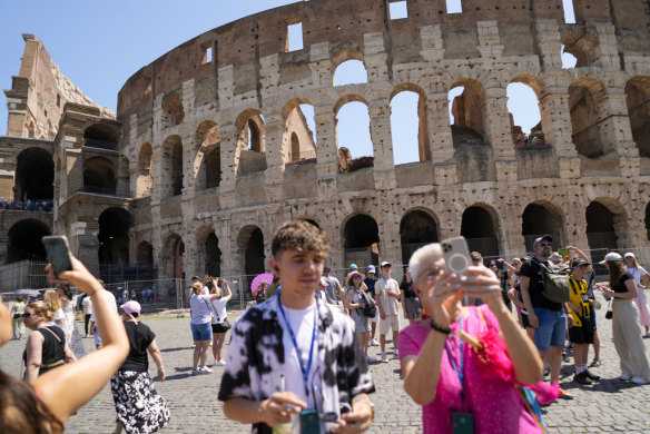Visitors take photos of the ancient Colosseum in Rome.
