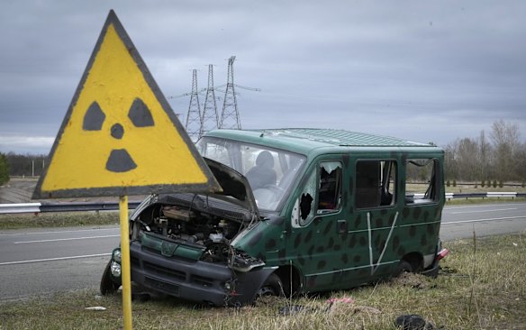 The remains of an abandoned vehicle bearing the V sign of the Russian army sits by a radiation sign close to the Chernobyl nuclear power.