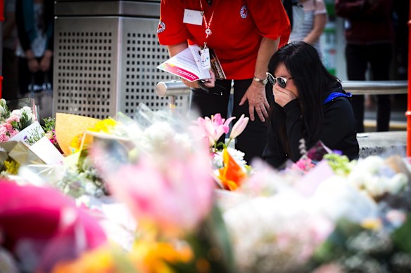 A member of the public lays flowers at the floral tribute to the victims.