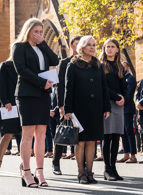 Family members watch on as the casket of Bob Fulton is loaded into a hearse.