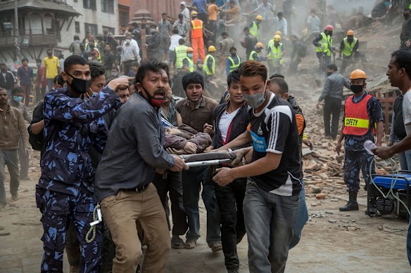 Emergency rescue workers carry a victim on a stretcher after Dharara tower collapsed on April 25, 2015 in Kathmandu, Nepal. 
