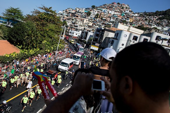 People watch on from the Vidigal favela as the Olympic torch passes by during the Olympic torch relay on August 5.