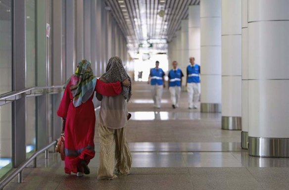 Family members (L) of those onboard the missing Malaysia Airlines flight walk into the waiting area at Kuala Lumpur International Airport in Sepang.