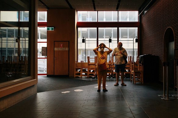 A couple put on face masks before entering the Broadway Shopping centre, Glebe. April 2 2020 