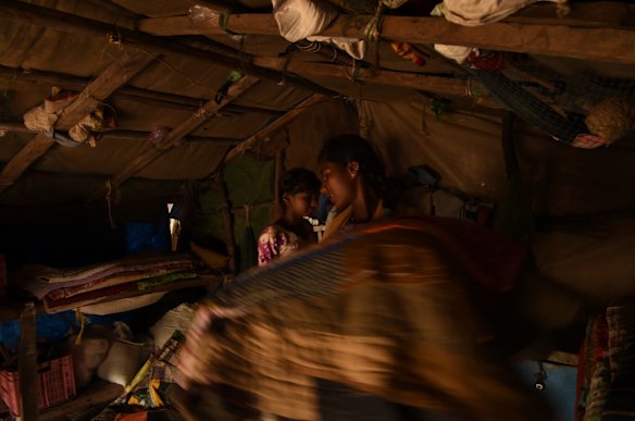 Girls prepare bedding in the fishing settlement of Tragadi Bandar, near Adani's Mundra port and power plant. During the dry season, several hundred people live here, sleeping on the coarse white sand in shacks made of hessian and driftwood.