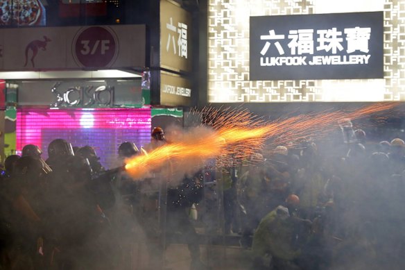 Policemen fire tear gas shells toward protesters at a shopping district.