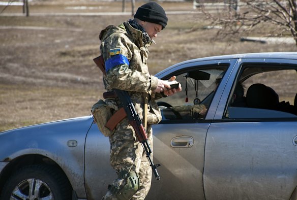 A Ukrainian serviceman checks documents of a driver in Kharkiv.