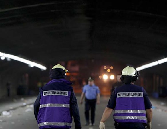 Psychologists walk through the tunnel where a stampede killed up to 18 people during a festival in Duisburg, Germany.