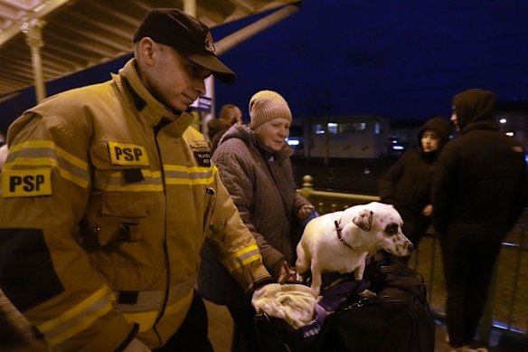 An elderly woman who fled Ukraine is helped at the train station in Przemysl, Poland, on Sunday.