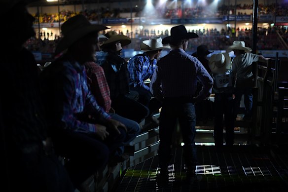 Competitors and their entourage watch events from behind the chutes at the Mount Isa Mines Rodeo.