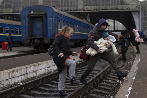 A family crosses the railway line as they continue their journey at the main bus and train terminal in Lviv.  