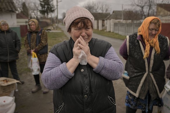 A woman cries while waiting for distribution of food products in the village of Motyzhyn, Ukraine, which until recently was under the control of the Russian military.
