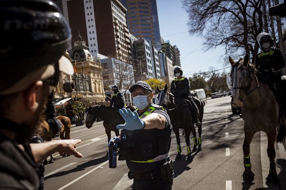 A protester confronting a police officer during the anti-lockdown rally, as he stands ready to deploy capsicum spray.
