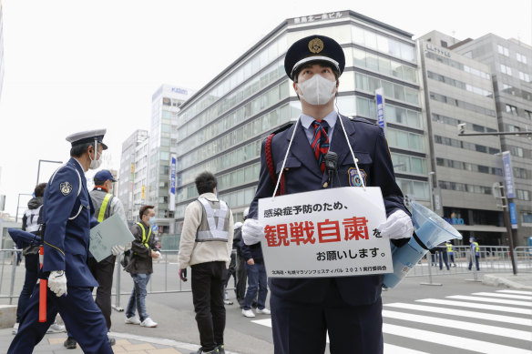 A security guard urges people not to watch a half-marathon in Sapporo in northern Japan on Wednesday to curb the spread of COVID-19.