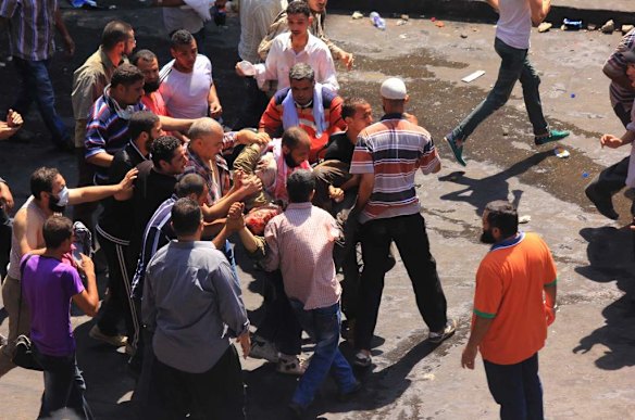 Supporters of Egypt's ousted President Mohammed Morsi carry a wounded comrade during clashes with security forces near the largest sit-in by supporters of Morsi in the eastern Nasr City district of Cairo, Egypt.