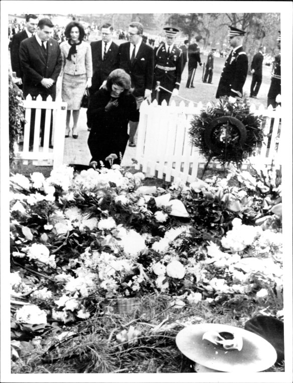 Jacqueline Kennedy kneels at her husband’s grave at Arlington National Cemetery.