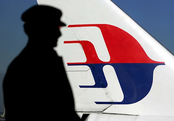 A file photo taken on July 5, 2005 shows a man silhouetted against a Malaysian Airlines plane tail as he looks out through a window at Sydney International Airport.