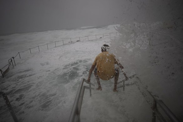 Wild weather at Bronte as a swimmer tries to enter the ocean pool.