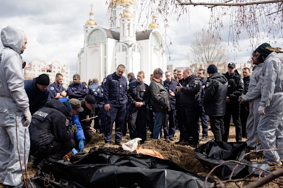 A forensic team exhume the bodies of a mother and two children buried by the church in Bucha.