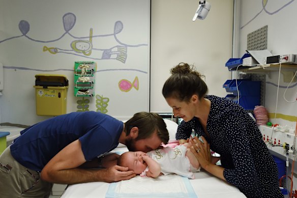 Six month old Aviana McElwee (center) laughs as she is entertained by her parents before she has a lumbar injection at the Sydney Children's Hospital.