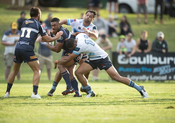 Brumbies' Irae Simone is tackled by the Waratahs' Karmichael Hunt and Curtis Rona.